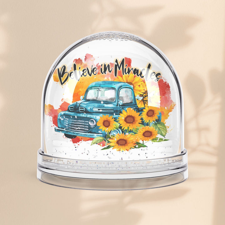 Sea Dragon Dreams Believe in Miracles snow globe featuring a vintage blue truck and sunflowers on a beige background.