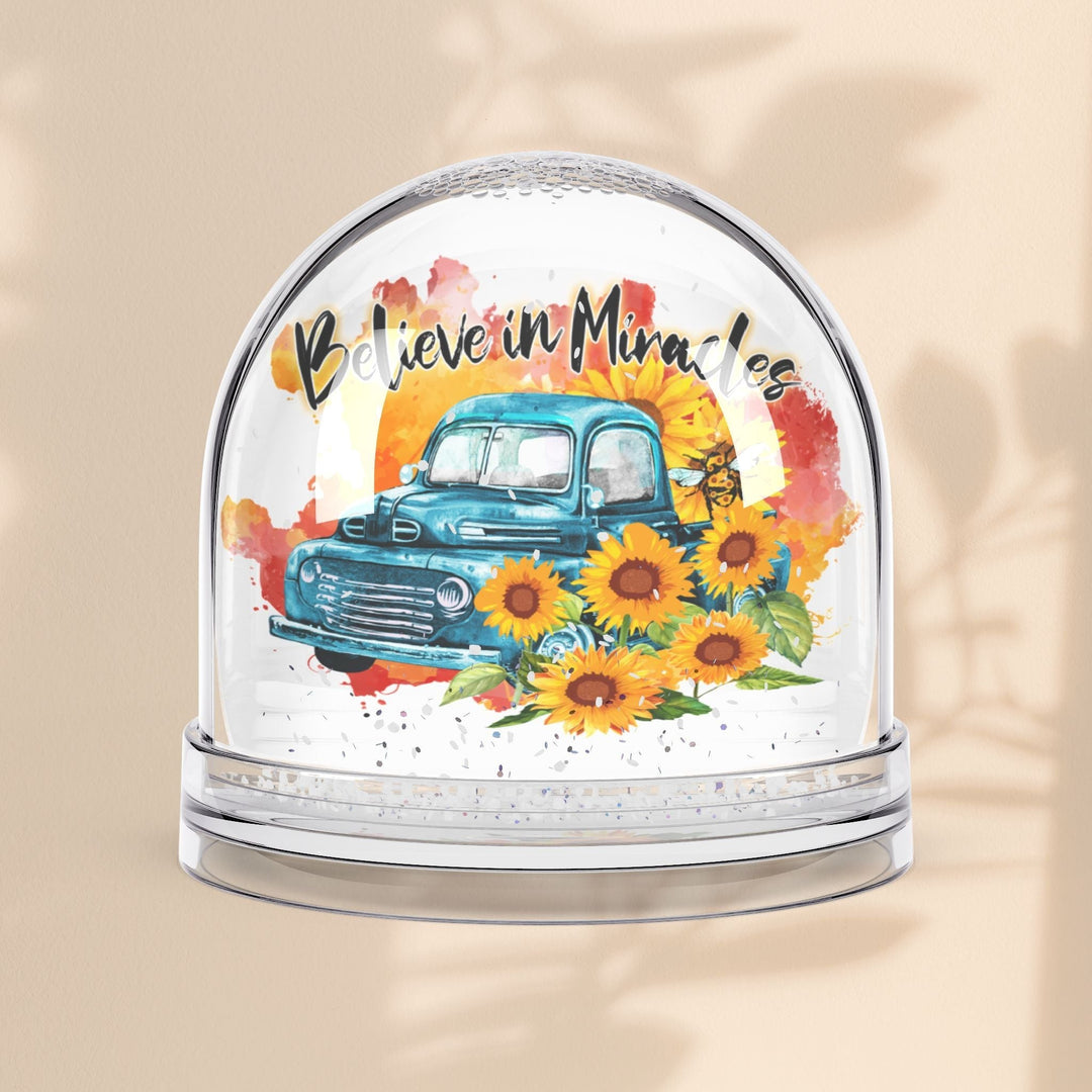 Sea Dragon Dreams snow globe featuring a vintage blue truck, sunflowers, and the text Believe in Miracles.