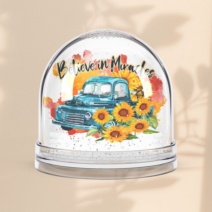 Sea Dragon Dreams snow globe featuring a vintage blue truck, sunflowers, and the text Believe in Miracles.