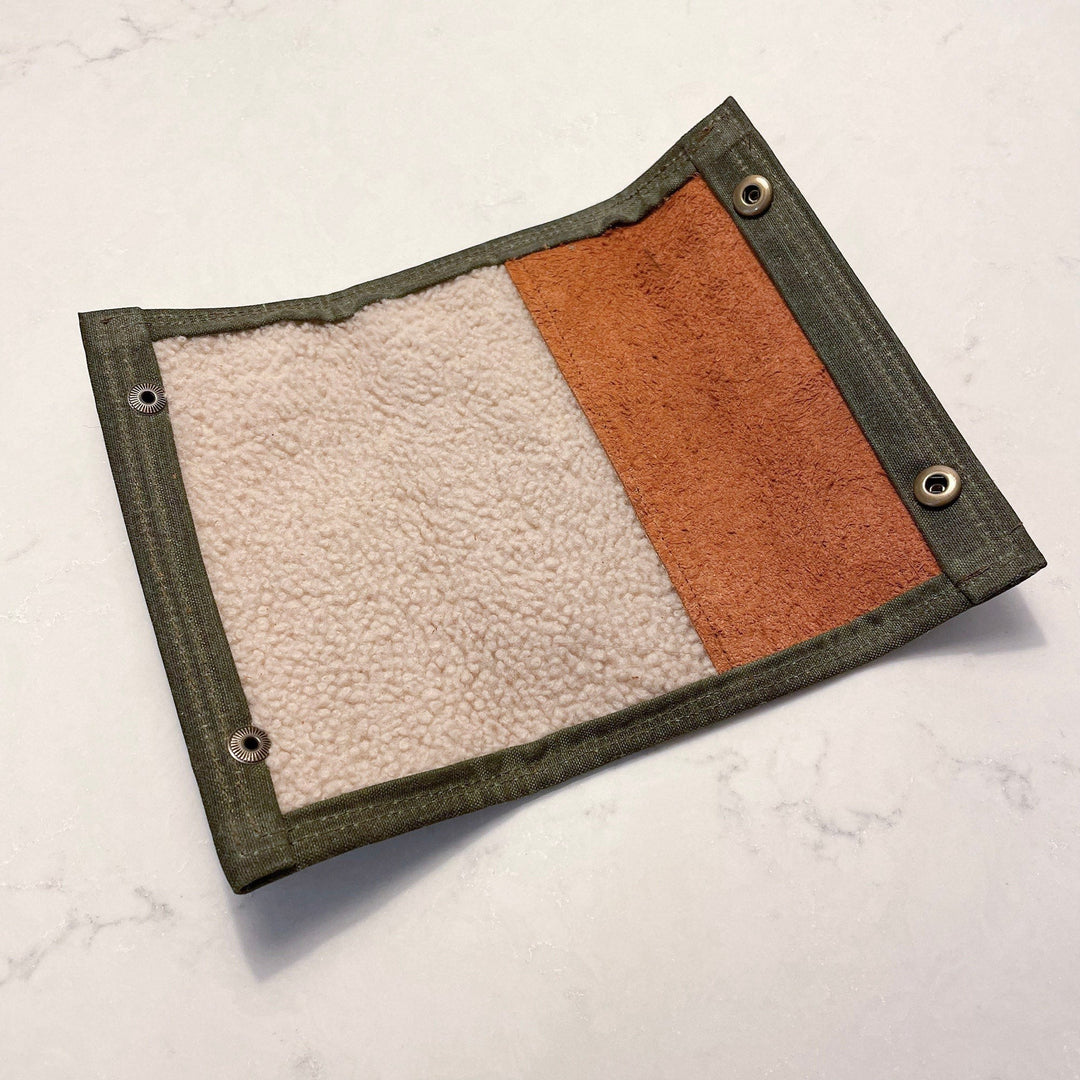 Sea Dragon Dreams waxed canvas fly fishing wallet open, showing cream shearling and brown suede interior with brass snaps