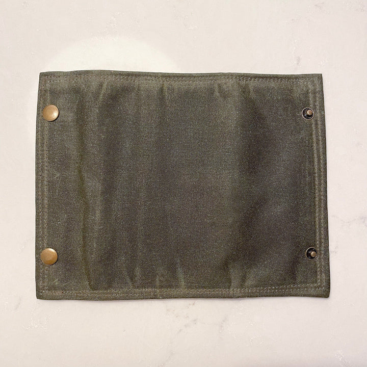 Sea Dragon Dreams olive green waxed canvas fly fishing wallet with brass snap closures, flat view.