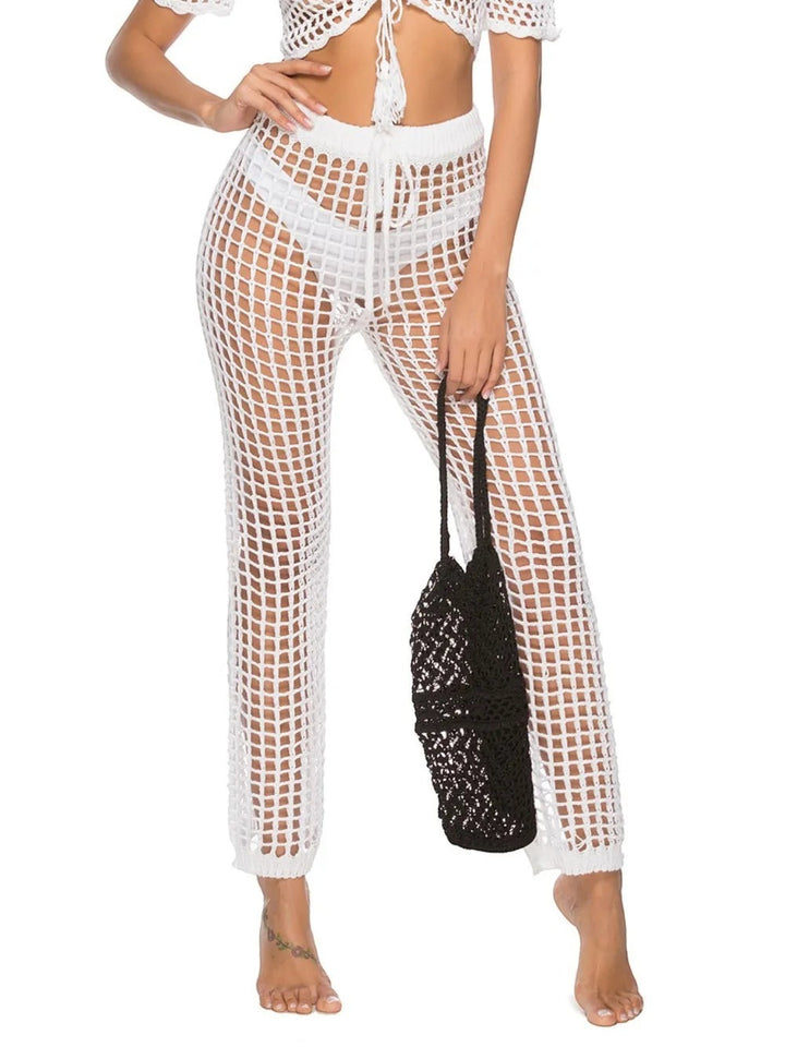 Sea Dragon Dreams white high-waisted crochet swim pants with cutout mesh design worn by a model with a black bag