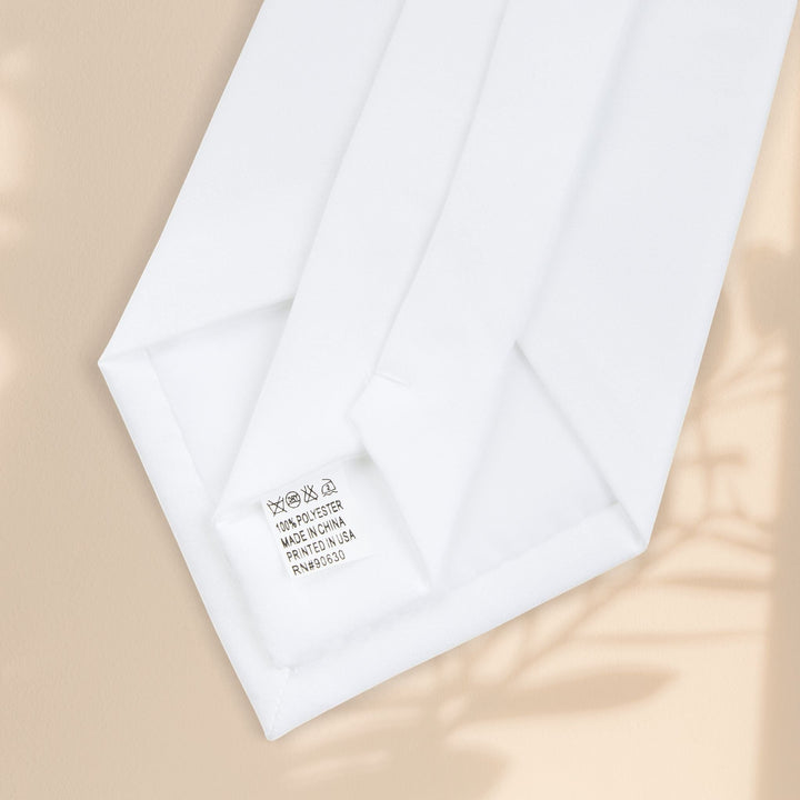 Sea Dragon Dreams white polyester necktie back view showing the sewn-in care label and V-shaped end on a tan background