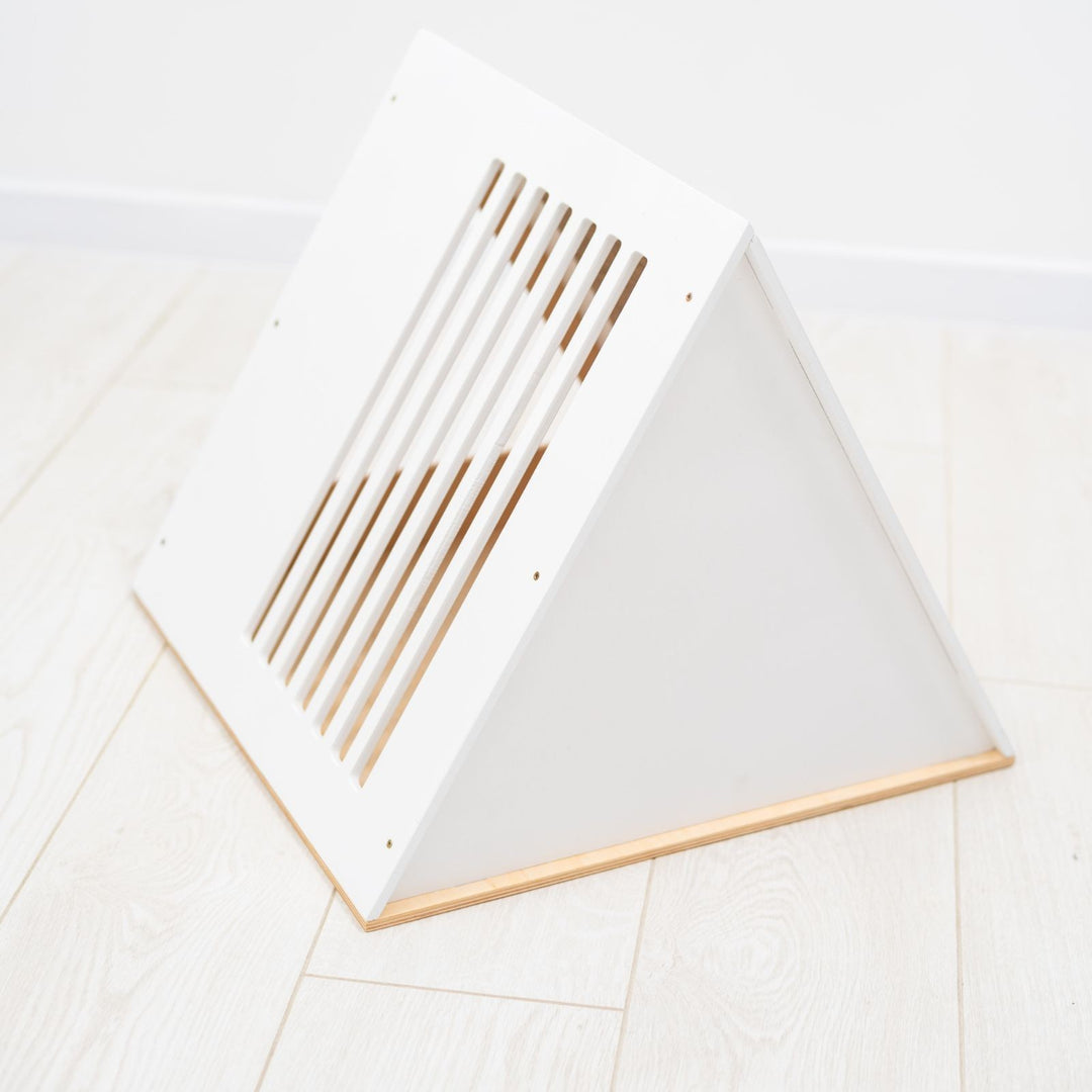 Sea Dragon Dreams modern white wooden cat house with a triangular shape and slatted side panel on a light floor.