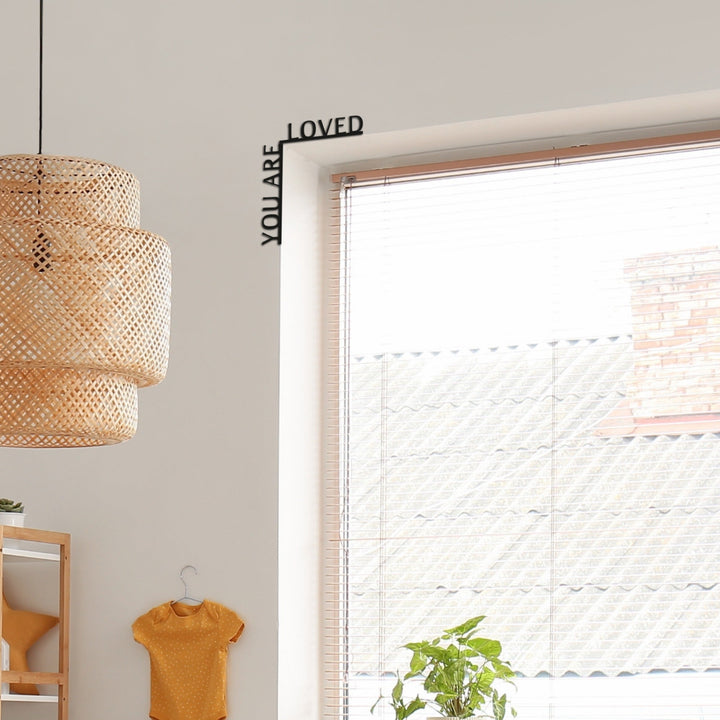 Sea Dragon Dreams black wooden corner sign with the quote You Are Loved mounted on a wall corner above a window.