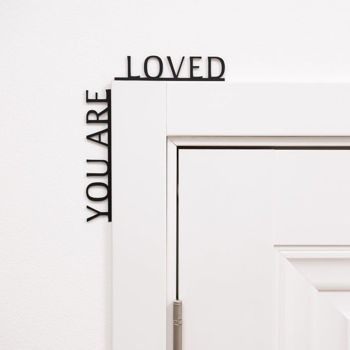 Sea Dragon Dreams black wooden corner sign with the inspirational quote You Are Loved mounted on a door frame.