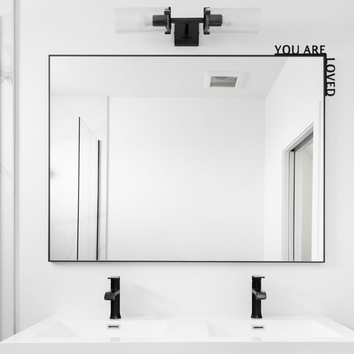 Sea Dragon Dreams You Are Loved wooden corner sign mounted on a modern bathroom mirror above a double vanity.