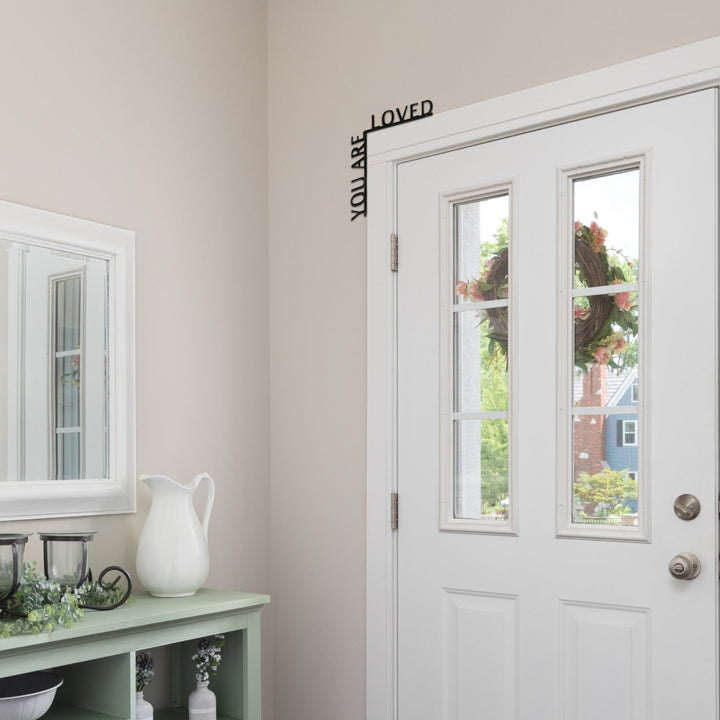 Sea Dragon Dreams You Are Loved black wooden corner sign mounted above a white door in a bright home entryway.