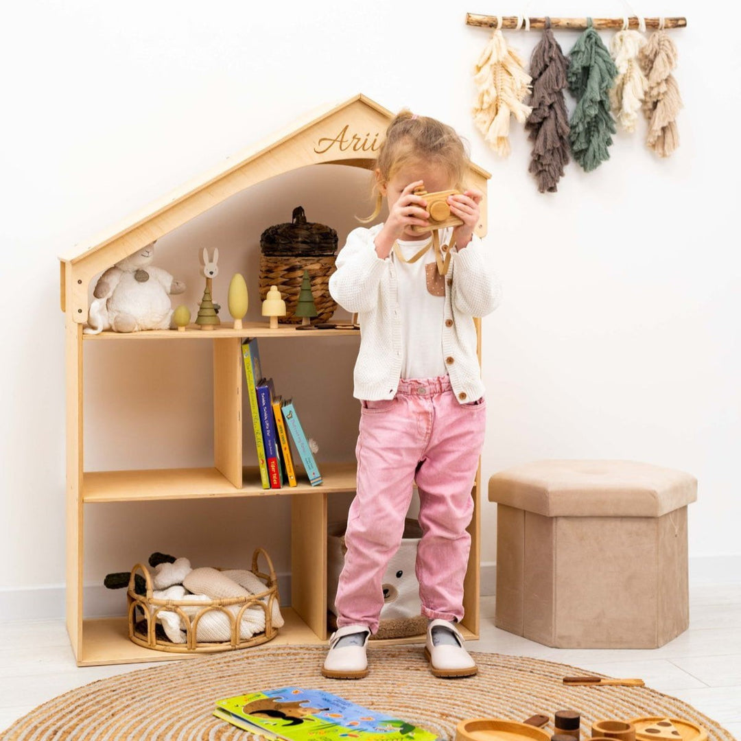 Sea Dragon Dreams personalized wooden dollhouse bookcase with a child playing in a bright, modern nursery playroom.