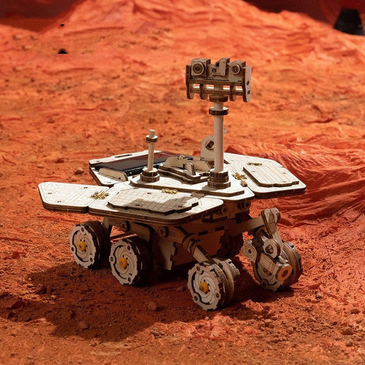 Sea Dragon Dreams wooden mechanical Mars rover puzzle model on a textured red surface