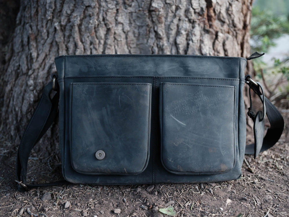 Sea Dragon Dreams Limited Edition Yukon leather messenger bag in dark grey with two front pockets against a tree trunk